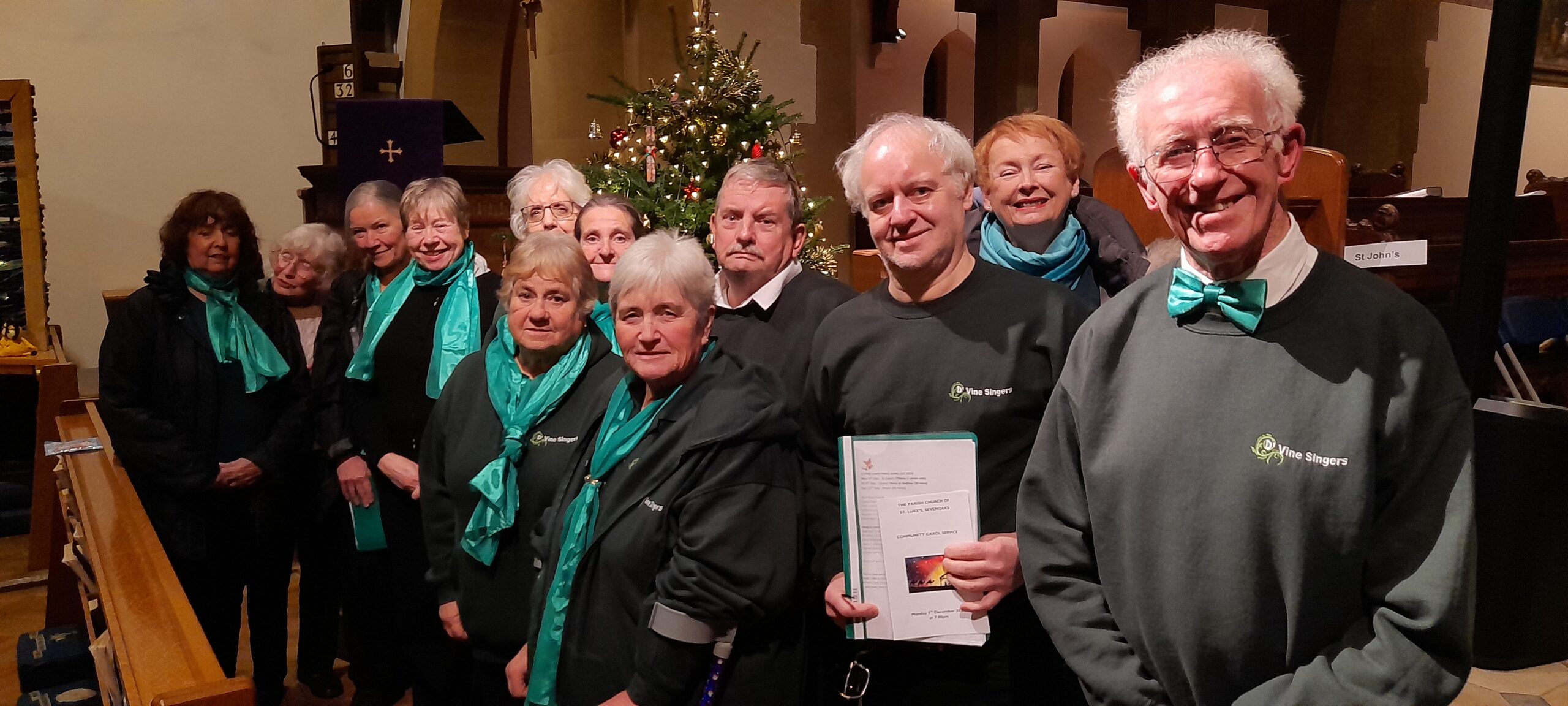 D'Vine singers standing in front of a Christmas tree
