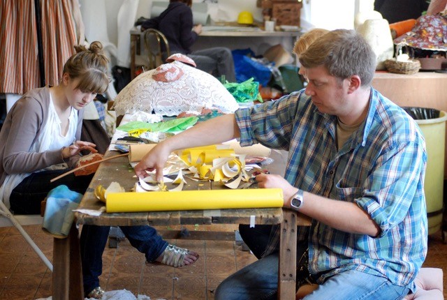 Two people creating an object out of paper